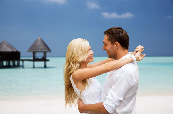 Casal feliz se divertindo na praia com bungalow — Fotografia de Stock