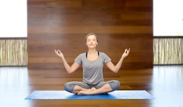 Kvinna att göra yoga meditation i lotus pose på matta — Stockfoto