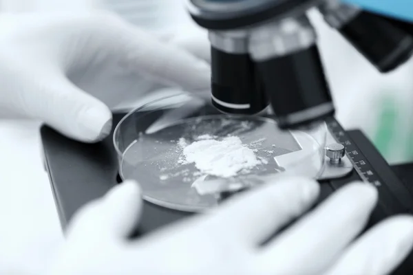 Primer plano de la mano con microscopio y muestra de polvo — Foto de Stock