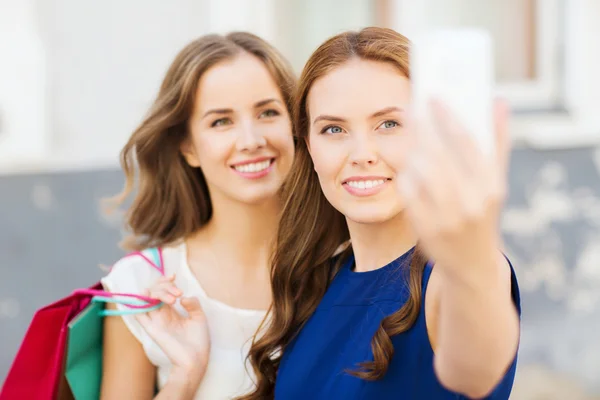 Mulheres felizes com sacos de compras e smartphone — Fotografia de Stock