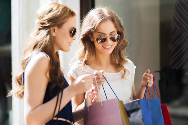 Mulheres felizes com sacos de compras na vitrine da loja — Fotografia de Stock