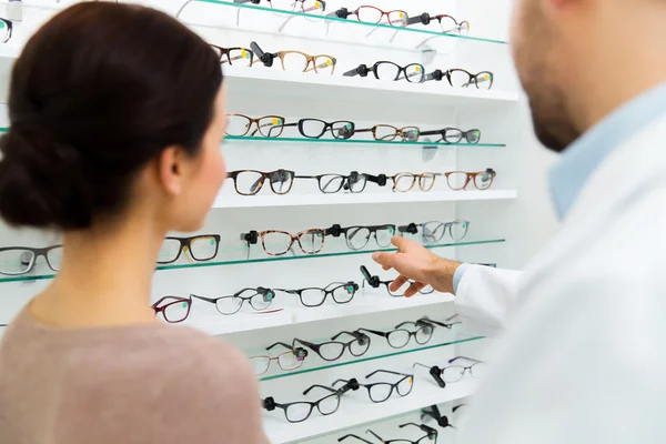 Optician showing glasses to woman at optics store — Stock Photo, Image