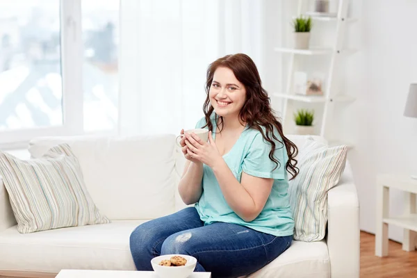 Happy plus size woman with cup and cookies at home — Stock Photo, Image
