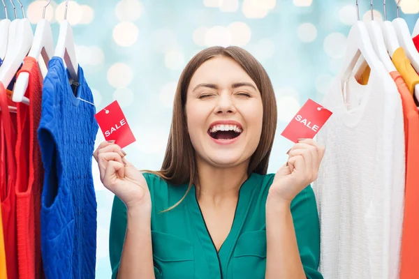 Mujer feliz con etiquetas de venta en la ropa en el armario — Foto de Stock