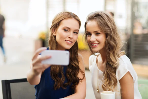 Mujeres felices con teléfono inteligente tomando selfie en la cafetería —  Fotos de Stock