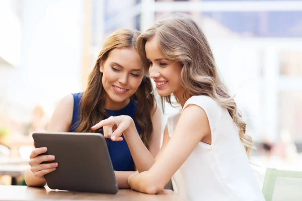 Счастливые молодые женщины с планшетным компьютером в открытом кафе — стоковое фото