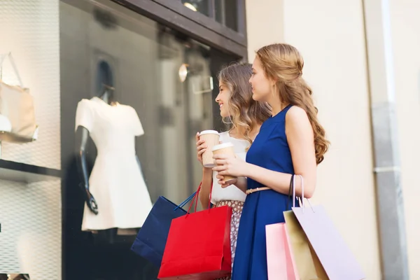 Jonge vrouwen met boodschappentassen en koffie bij shop — Stockfoto