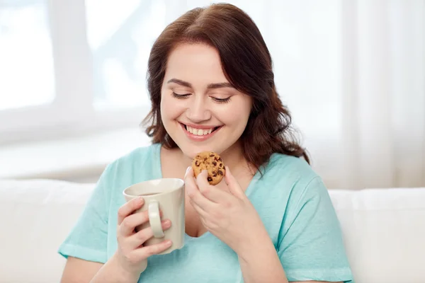 Happy plus size woman with cup and cookie at home — Stock Photo, Image