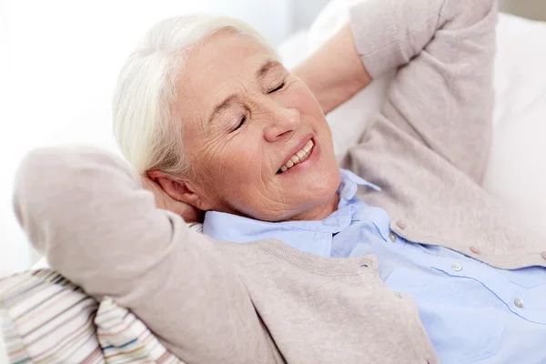 Счастливая пожилая женщина отдыхает дома на диване — стоковое фото