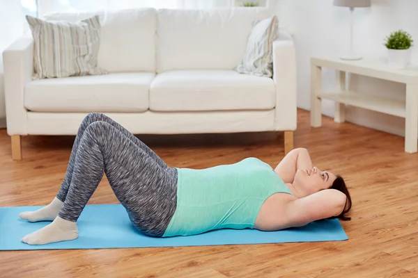 Mulher plus size exercitando-se no tapete em casa — Fotografia de Stock
