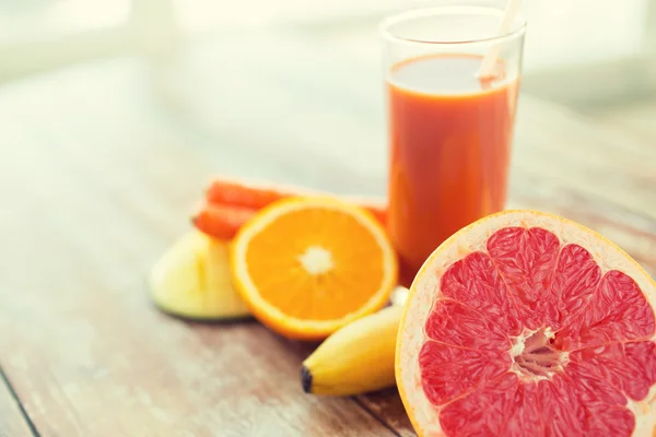 Close up of fresh juice glass and fruits on table — Stock Photo, Image