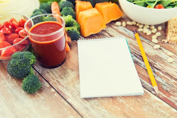 Close up of ripe vegetables and notebook on table — Stock Photo, Image