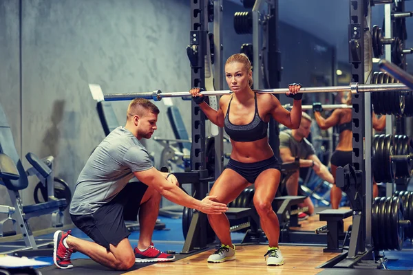 Homem e mulher com músculos de flexão barbell no ginásio — Fotografia de Stock