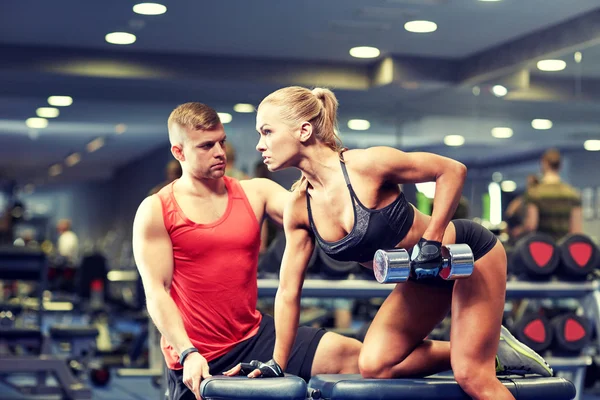 Giovane coppia con manubri che flettono i muscoli in palestra — Foto Stock