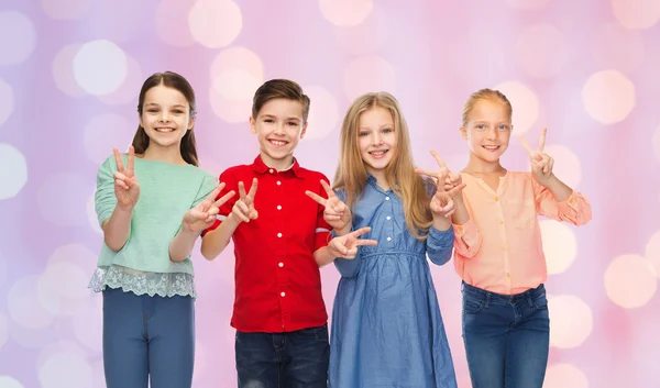 Niño feliz y las niñas mostrando la paz signo de mano —  Fotos de Stock