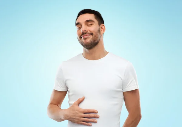 Happy full man touching tummy over blue background — Stock Photo, Image