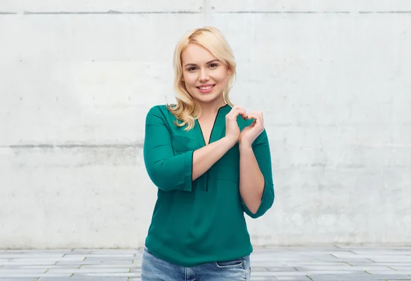 Lachende jonge vrouw in hemd tonen hart vorm — Stockfoto