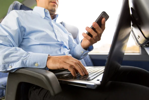 Man with smartphone and laptop in travel bus — Stock Photo, Image