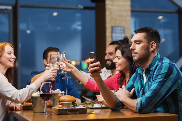 Чоловік зі смартфоном і друзями в ресторані — стокове фото