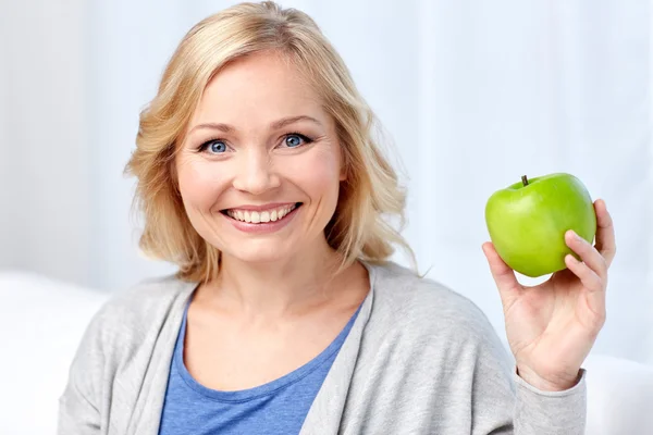 Gelukkig midden leeftijd vrouw met groene apple thuis — Stockfoto