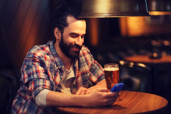 Hombre con teléfono inteligente y cerveza mensajes de texto en el bar —  Fotos de Stock