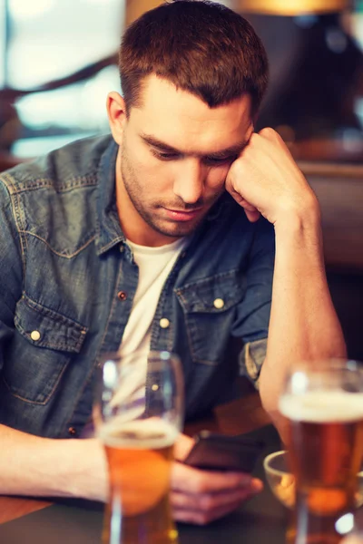 Man met smartphone en bier texting op bar — Stockfoto