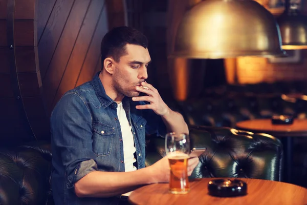 Homem bebendo cerveja e fumando cigarro no bar — Fotografia de Stock