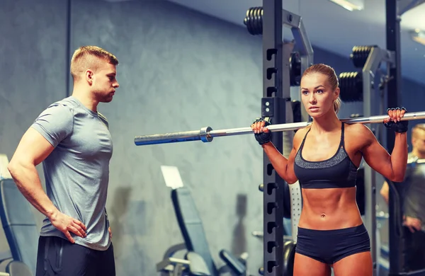 Man en vrouw met lange halter flexing spieren in de sportschool — Stockfoto