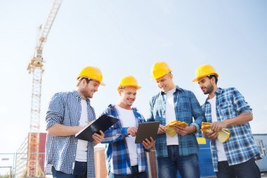 group of smiling builders with tablet pc outdoors clipart