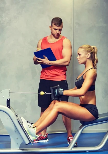 Hombres y mujeres flexionando los músculos en la máquina de gimnasio — Foto de Stock