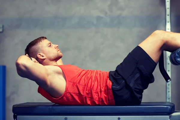 Hombre joven haciendo ejercicios abdominales en el gimnasio — Foto de Stock