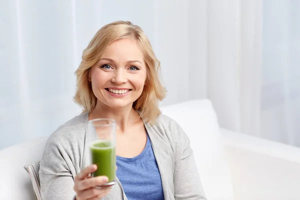 Mulher feliz beber suco verde ou agitar em casa — Fotografia de Stock