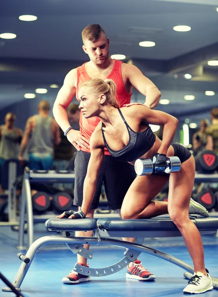 Jovem casal com haltere músculos flexores no ginásio — Fotografia de Stock