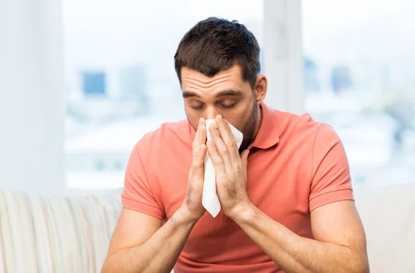 Sick man blowing nose to paper napkin at home — Stock Photo, Image