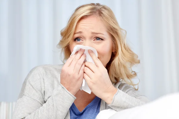 Ill woman blowing nose to paper napkin — Stock Photo, Image