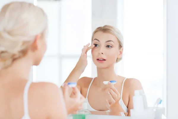 Junge Frau setzt Kontaktlinsen im Badezimmer auf — Stockfoto