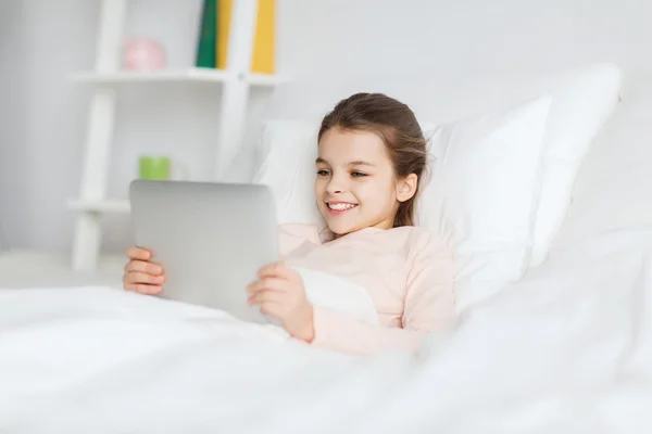 Šťastná dívka leží v posteli s tablet pc doma — Stock fotografie