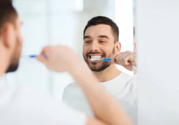 Man met tandenborstel reiniging van de tanden in de badkamer — Stockfoto