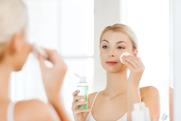 Mujer joven con la cara de lavado de loción en el baño — Foto de Stock