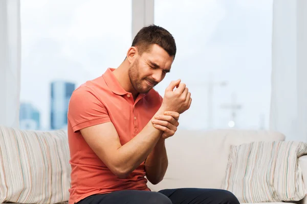 Unhappy man suffering from pain in hand at home — Stock Photo, Image