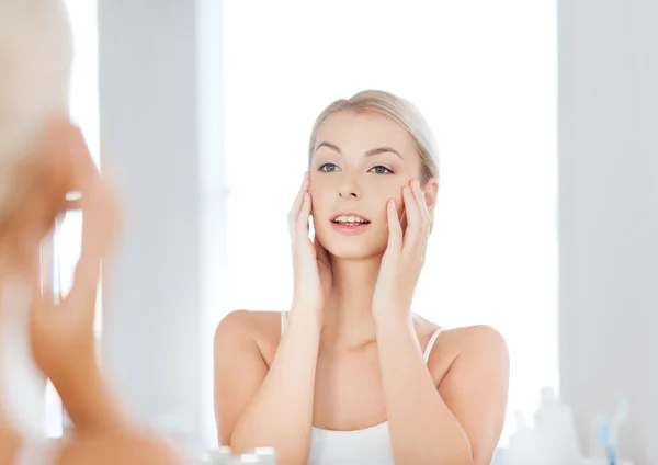 Feliz joven mujer mirando al espejo en el baño —  Fotos de Stock