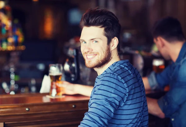 Szczęśliwy młody człowiek picia piwa w barze lub pubie — Zdjęcie stockowe