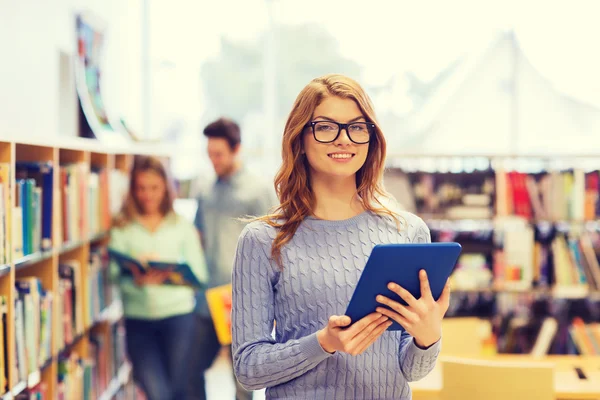 Felice studentessa con tablet pc in biblioteca — Foto Stock