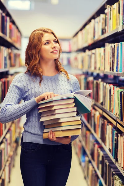 Menina estudante feliz ou mulher com livros na biblioteca — Fotografia de Stock