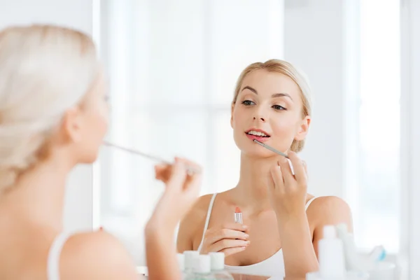 Kvinna med läppstift tillämpa make up på badrum — Stockfoto