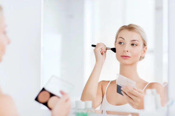 Žena s make-up štětce a nadace v koupelně — Stock fotografie