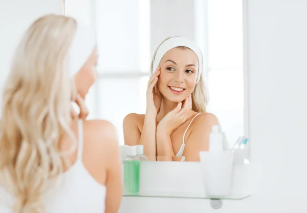 Frau mit Haarband berührt ihr Gesicht im Badezimmer — Stockfoto