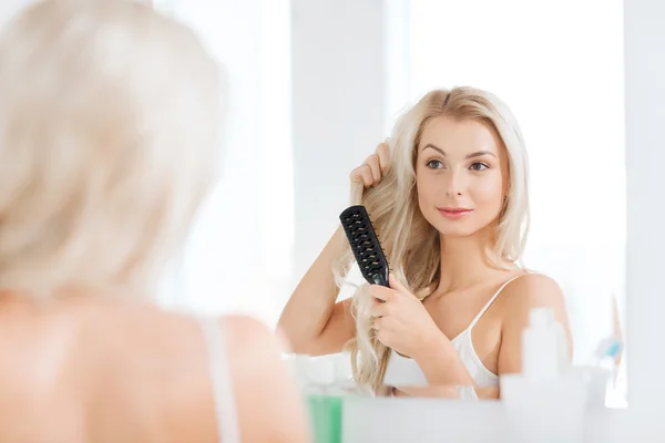 Mulher feliz escovar o cabelo com pente no banheiro — Fotografia de Stock