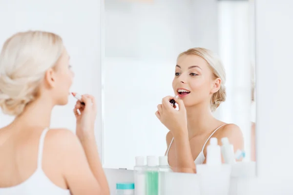 Kvinna med läppstift tillämpa make up på badrum — Stockfoto