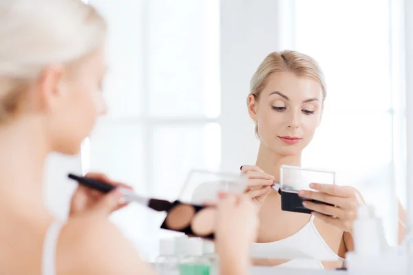 Mujer con cepillo de maquillaje y fundación en el baño — Foto de Stock